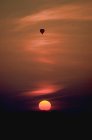 Hot-air balloon silhouetted with setting sun