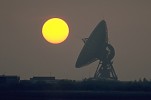 Satellite receiver dish with setting sun, England