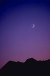 Crescent-moon in dusk sky over mountain ridge